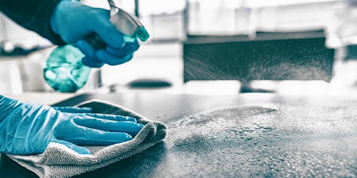 person disinfecting a surface with hypochlorous acid