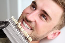 Man's smile compared with tooth color chart