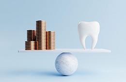 Gold coins and a model tooth placed on a balance beam