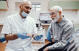A dentist showing a denture to his patient