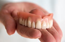 A closeup of a hand holding a removable denture