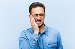 Man with tooth pain wearing denim shirt and glasses