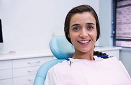 Woman with brown hair smiling in dental chair