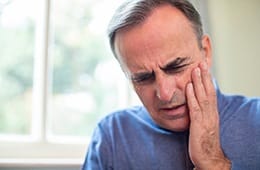 Man with dental pain in blue shirt