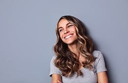 Woman smiling looking away in grey shirt