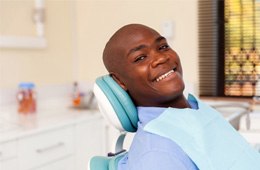 a smiling man sitting in a dental chair