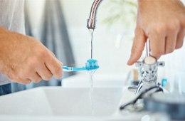 a person putting water on their toothbrush