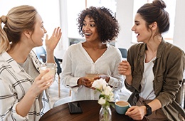 Patient smiling with friends over coffee after fluoride treatment