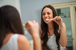 Woman with dental implants in Campbell, CA brushing her teeth