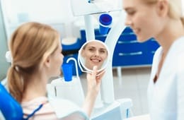 A woman looking at her smile in the mirror