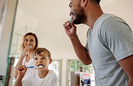 Family brushing teeth together at home