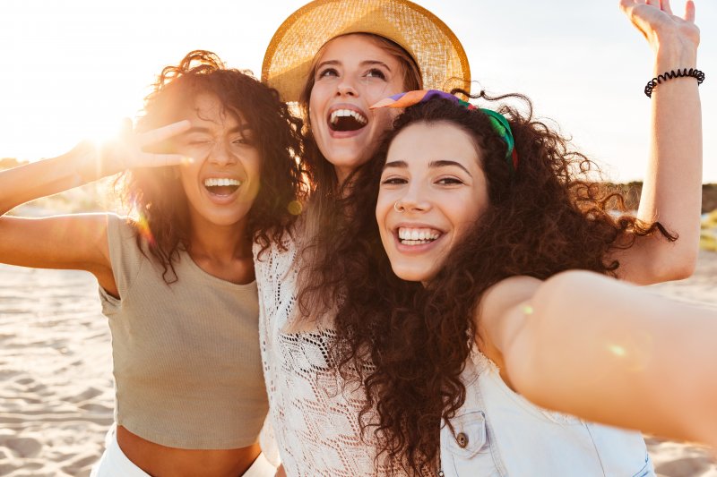 Three young women smiling in the summer sun on a beach
