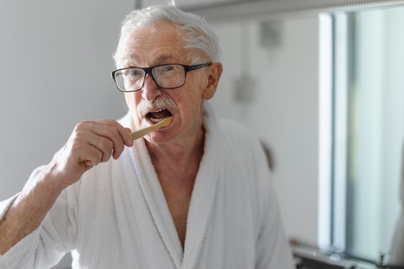 Older man brushing his teeth to prevent gum disease